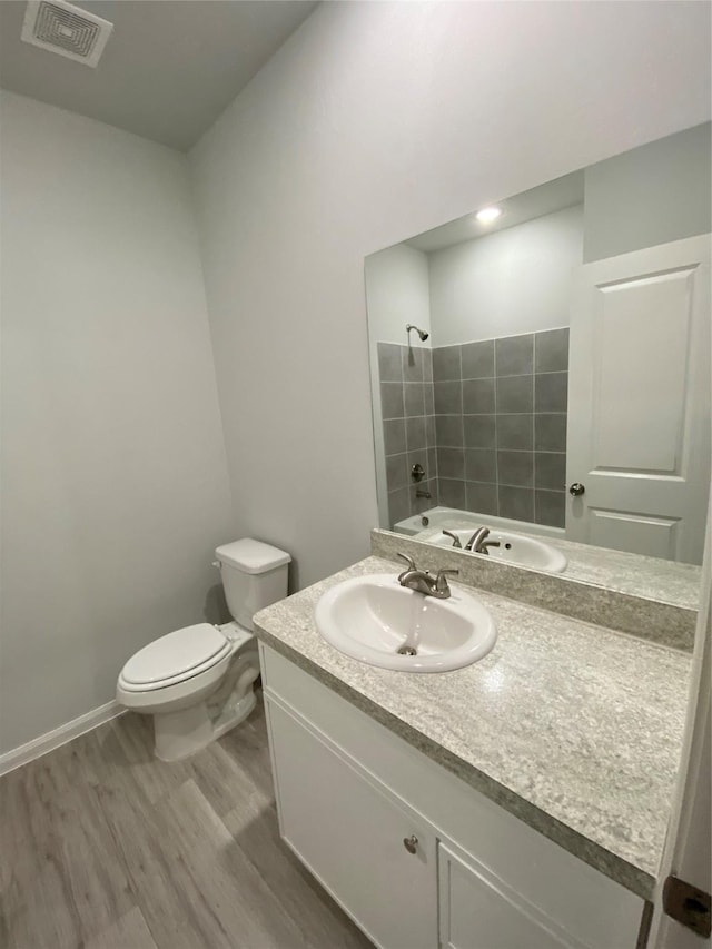 bathroom with walk in shower, vanity, toilet, and hardwood / wood-style floors