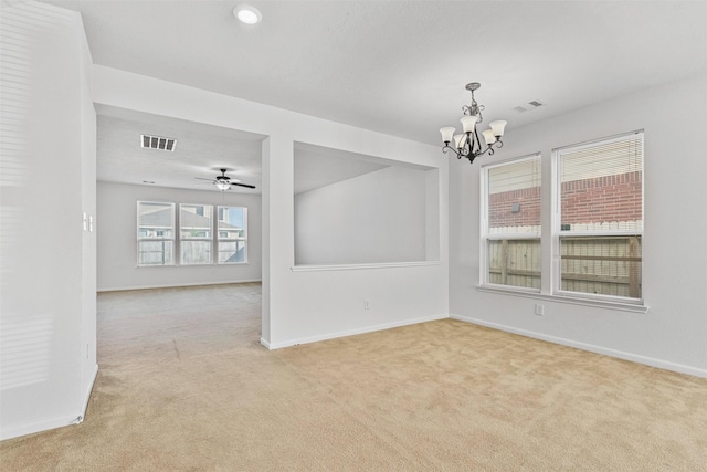 carpeted empty room with ceiling fan with notable chandelier