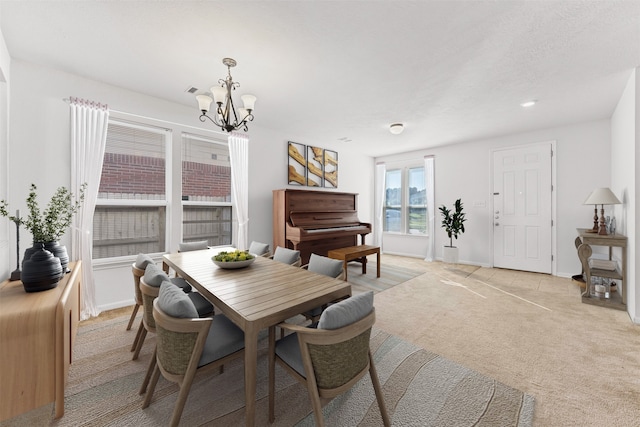 dining room featuring an inviting chandelier, light colored carpet, and a textured ceiling