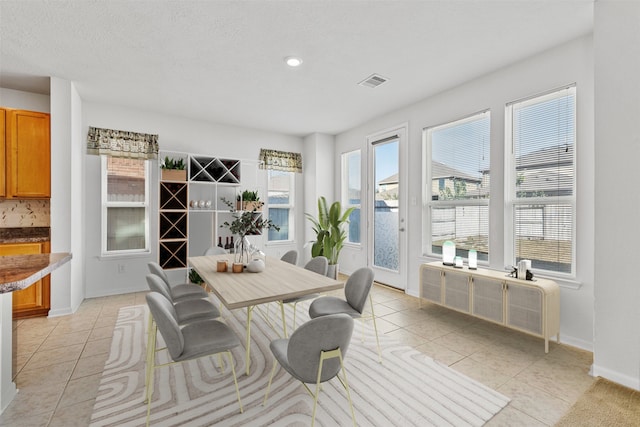 dining area featuring light tile patterned floors and a textured ceiling