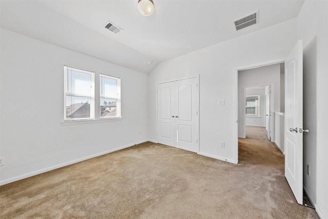 unfurnished bedroom with lofted ceiling, light colored carpet, and a closet