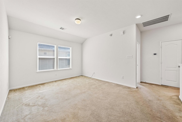 carpeted spare room featuring vaulted ceiling