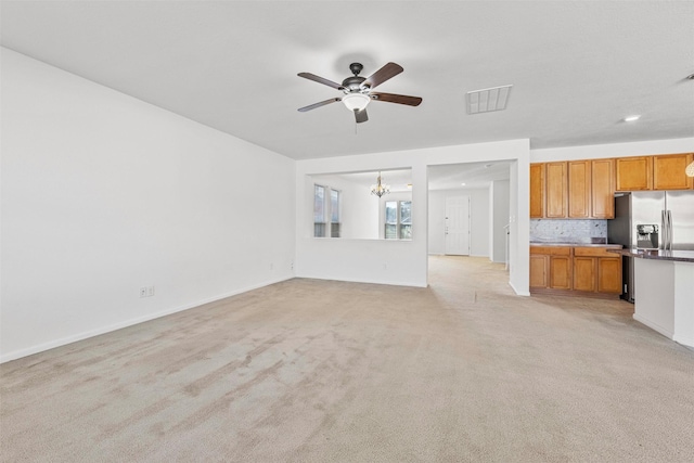 unfurnished living room featuring light colored carpet and ceiling fan with notable chandelier