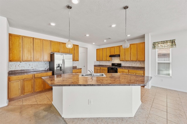 kitchen with black gas stove, sink, pendant lighting, and stainless steel fridge