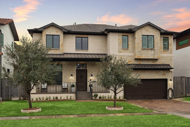 view of front of house with a garage, a yard, and covered porch