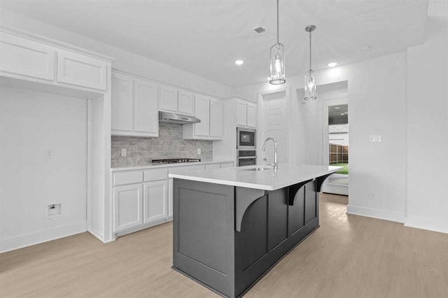 kitchen with white cabinetry, decorative light fixtures, a kitchen island with sink, and stainless steel appliances