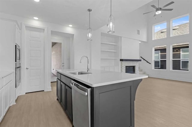 kitchen featuring sink, hanging light fixtures, dishwasher, an island with sink, and white cabinets