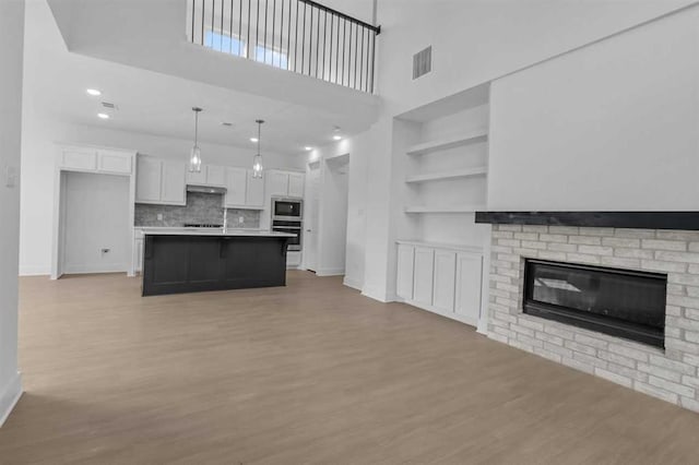 unfurnished living room with a fireplace, built in features, and light wood-type flooring