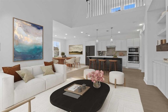 living room featuring a towering ceiling and light wood-type flooring