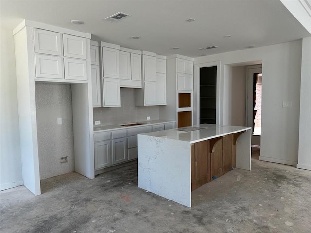 3318 Verdant, Richmond, TX 77406 - kitchen featuring unfinished concrete floors, a center island, backsplash, and white cabinets
