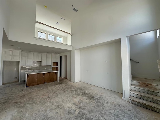 3318 Verdant, Richmond, TX 77406 - unfurnished living room with a high ceiling, stairway, and unfinished concrete floors