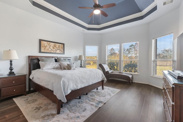 bedroom with a tray ceiling, ornamental molding, dark hardwood / wood-style floors, and ceiling fan