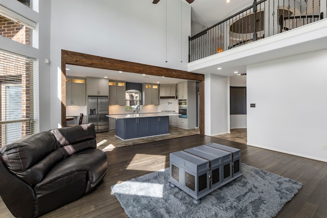 living room with ceiling fan, a towering ceiling, and dark hardwood / wood-style flooring