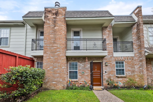 view of front of house featuring brick siding, a shingled roof, and fence