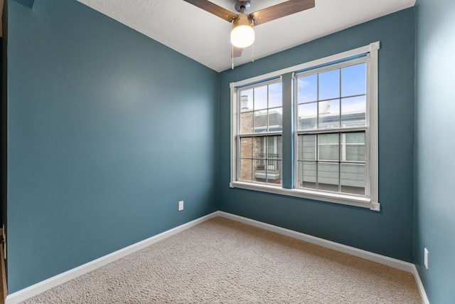 carpeted empty room featuring baseboards and a ceiling fan