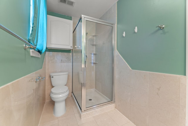 bathroom with a shower stall, visible vents, tile walls, and tile patterned floors