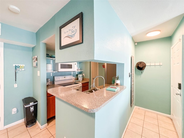 kitchen featuring sink, light tile patterned floors, white appliances, and kitchen peninsula