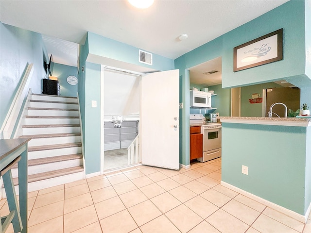 kitchen featuring light tile patterned floors and white appliances