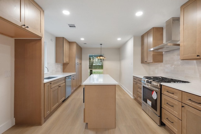 kitchen with sink, hanging light fixtures, a center island, stainless steel appliances, and wall chimney range hood