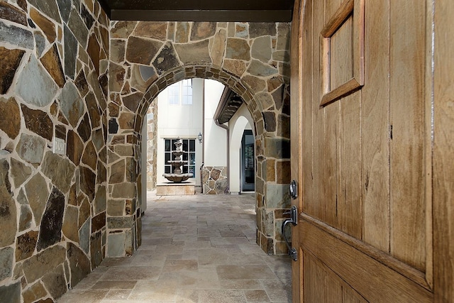 hallway featuring stone tile flooring and arched walkways