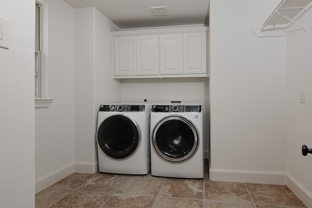 clothes washing area featuring baseboards, visible vents, washer and dryer, and cabinet space