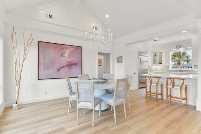 dining room featuring a notable chandelier, high vaulted ceiling, and light hardwood / wood-style flooring