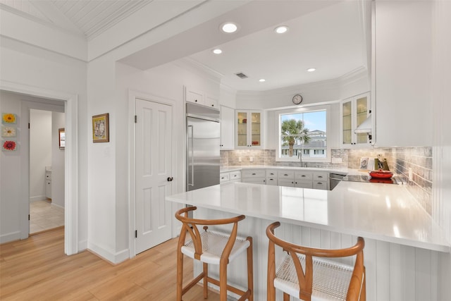 kitchen with a breakfast bar, tasteful backsplash, white cabinetry, kitchen peninsula, and stainless steel appliances