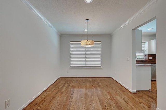 unfurnished dining area featuring crown molding, a textured ceiling, and light hardwood / wood-style floors