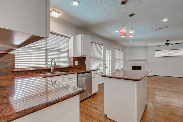 kitchen featuring pendant lighting, sink, light hardwood / wood-style floors, white cabinets, and stainless steel dishwasher