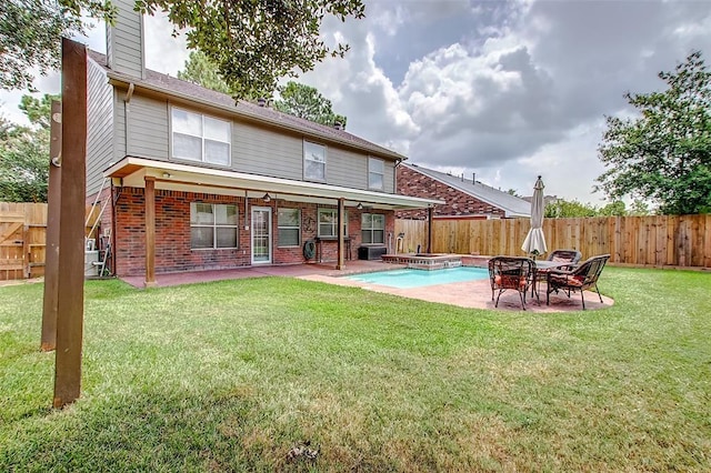 rear view of house with an in ground hot tub, a yard, and a patio area