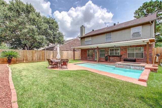 rear view of house with a yard, a fenced in pool, and a patio