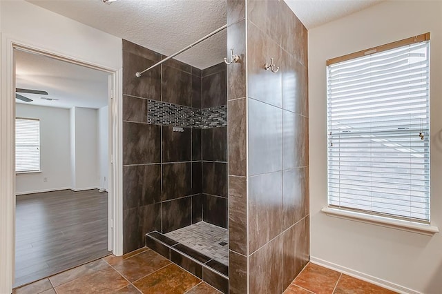 bathroom with tile patterned flooring, a tile shower, and a textured ceiling