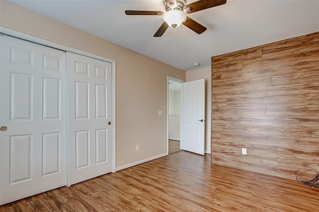 unfurnished bedroom with ceiling fan, light wood-type flooring, and a closet