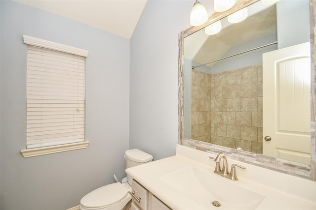 bathroom with vanity, lofted ceiling, a tile shower, and toilet