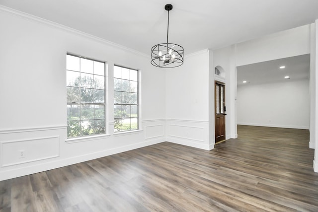 unfurnished dining area with an inviting chandelier, ornamental molding, and dark wood-type flooring