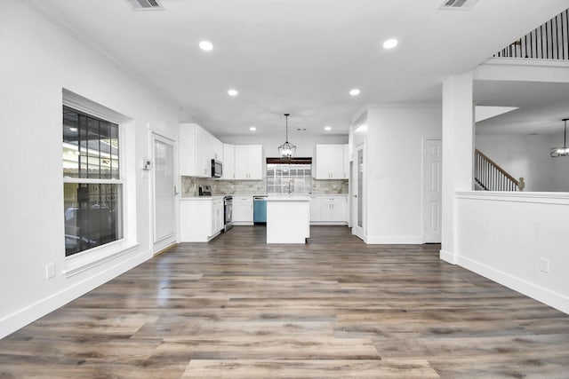 kitchen featuring pendant lighting, white cabinetry, stainless steel appliances, a center island, and decorative backsplash