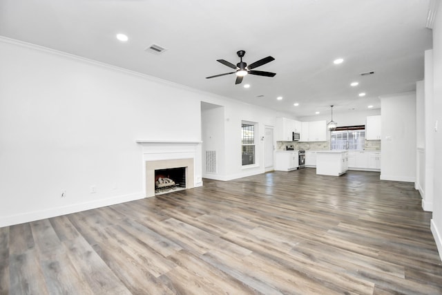 unfurnished living room with ornamental molding, hardwood / wood-style floors, and ceiling fan