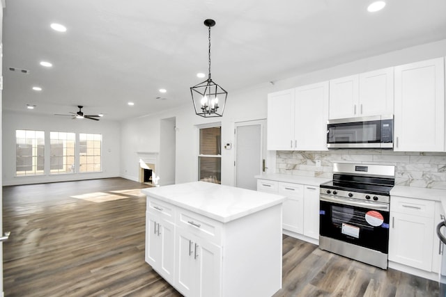 kitchen with a center island, pendant lighting, stainless steel appliances, decorative backsplash, and white cabinets