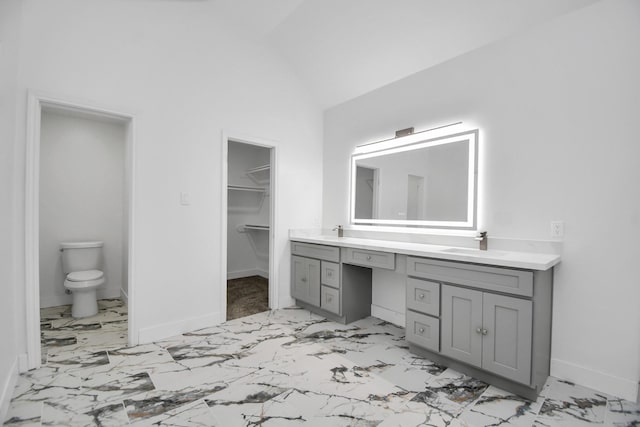 bathroom featuring vanity, vaulted ceiling, and toilet