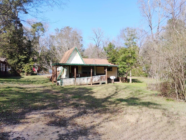 back of house with covered porch, a yard, and metal roof