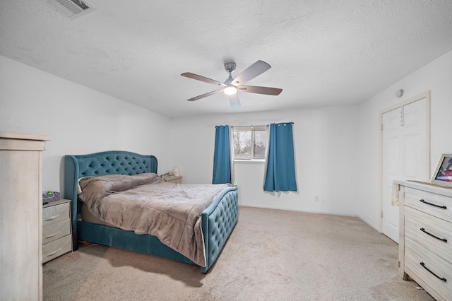 bedroom with ceiling fan, light carpet, and a textured ceiling