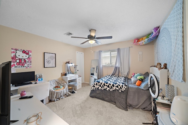 carpeted bedroom with ceiling fan and a textured ceiling