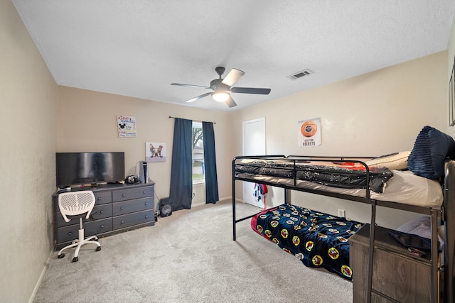 carpeted bedroom featuring ceiling fan and a textured ceiling