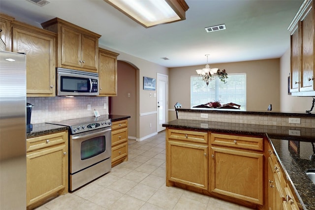 kitchen with tasteful backsplash, light tile patterned floors, dark stone countertops, pendant lighting, and stainless steel appliances