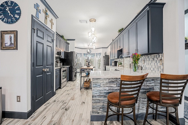 kitchen with decorative backsplash, a kitchen breakfast bar, kitchen peninsula, and appliances with stainless steel finishes