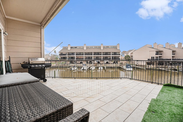 view of patio with area for grilling, a balcony, and a water view