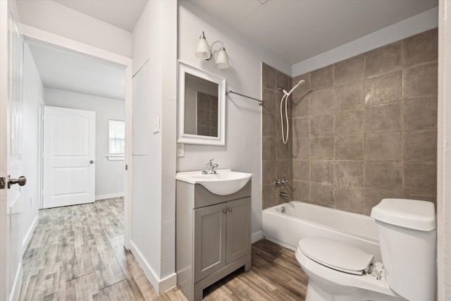 full bathroom featuring vanity, hardwood / wood-style floors, tiled shower / bath combo, and toilet