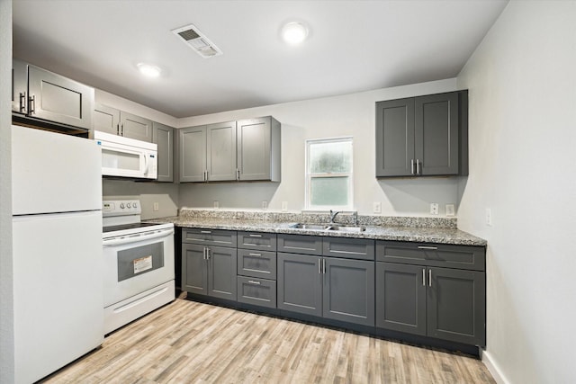 kitchen featuring sink, gray cabinetry, light hardwood / wood-style flooring, white appliances, and light stone countertops