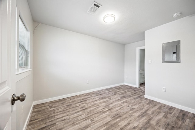 unfurnished room featuring hardwood / wood-style flooring and electric panel