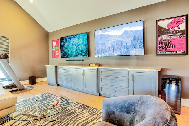 interior space with vaulted ceiling, light wood-style flooring, and baseboards